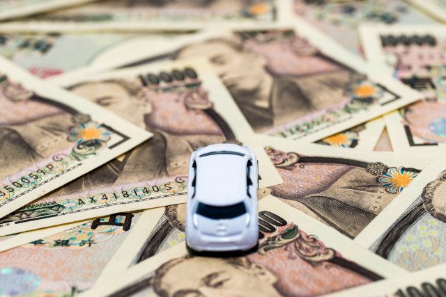 お金の上に置かれたミニカー