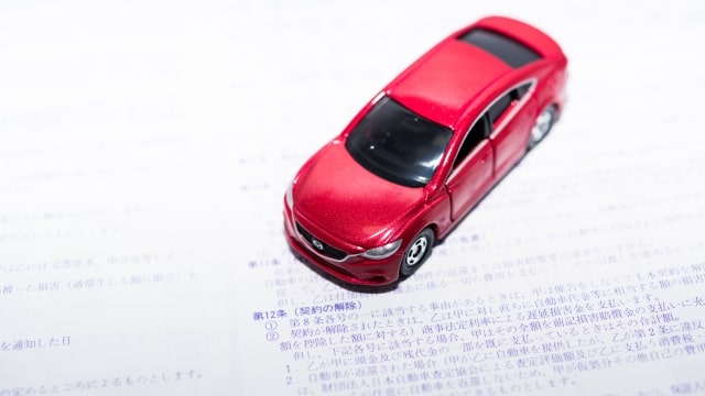書類と赤い車の模型